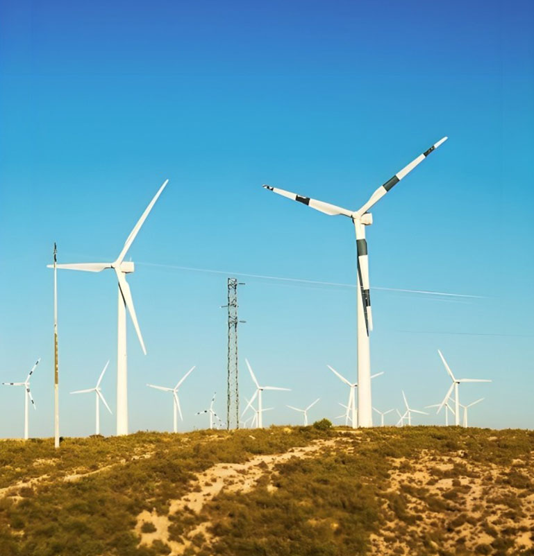 Windmill towers on a dry landscape under a clear blue sky, representing the quality output of top windmill tower manufacturers in India.